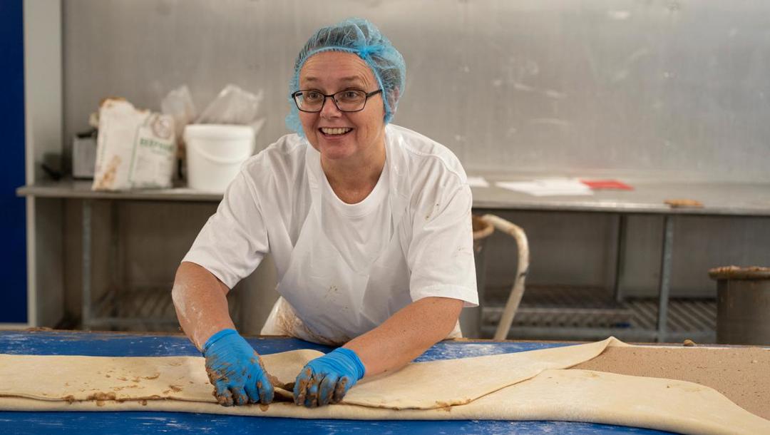 Pia Christensen lægger dejen til de populære kanelsnurrer sammen i tre lag. Hun har tidligere arbejdet 25 år ved en bager, og nu passer det hende rigtig godt at arbejde om dagen og få sin nattesøvn.